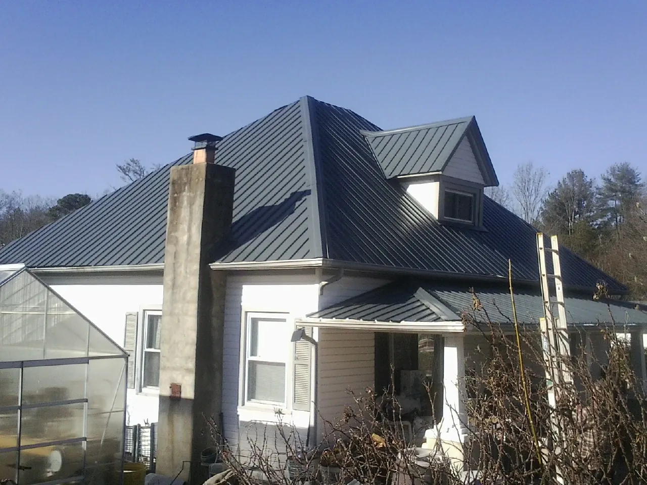 Dark blue standing seam metal roof on a white farmhouse with dormer — Slate & Tile Roof Repair by Roofing Brothers in Bicknell