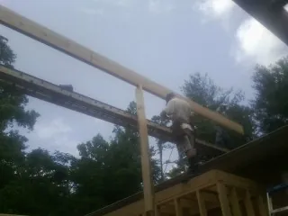 Carpenter setting a ridge beam over a new addition frame — Ice Dam Removal by Roofing Brothers in Bicknell