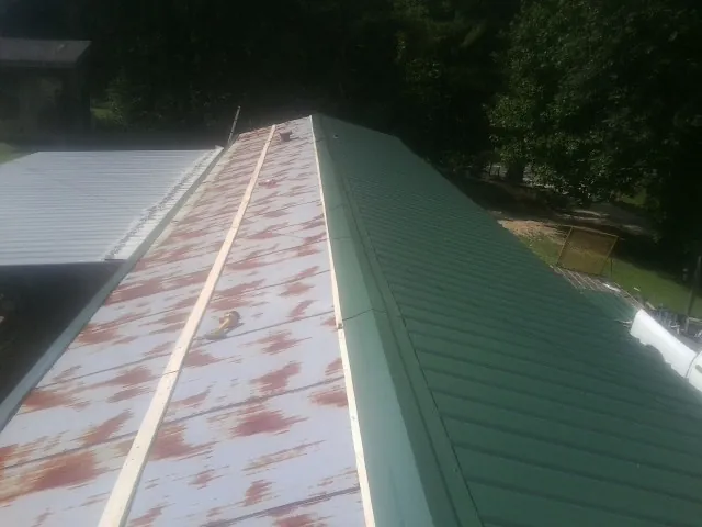Old rusted panels beside newly installed green metal roofing — Wind Damage Roof Repair by Roofing Brothers in Bicknell
