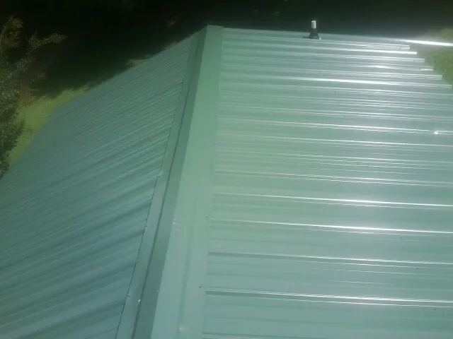 New green metal panels meeting at the ridge of a roof — Flat Roof Repair work by our crew in Bicknell