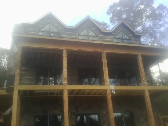Dormers and porch framing on a large log home under construction — Roof Coating work by our crew in Bicknell