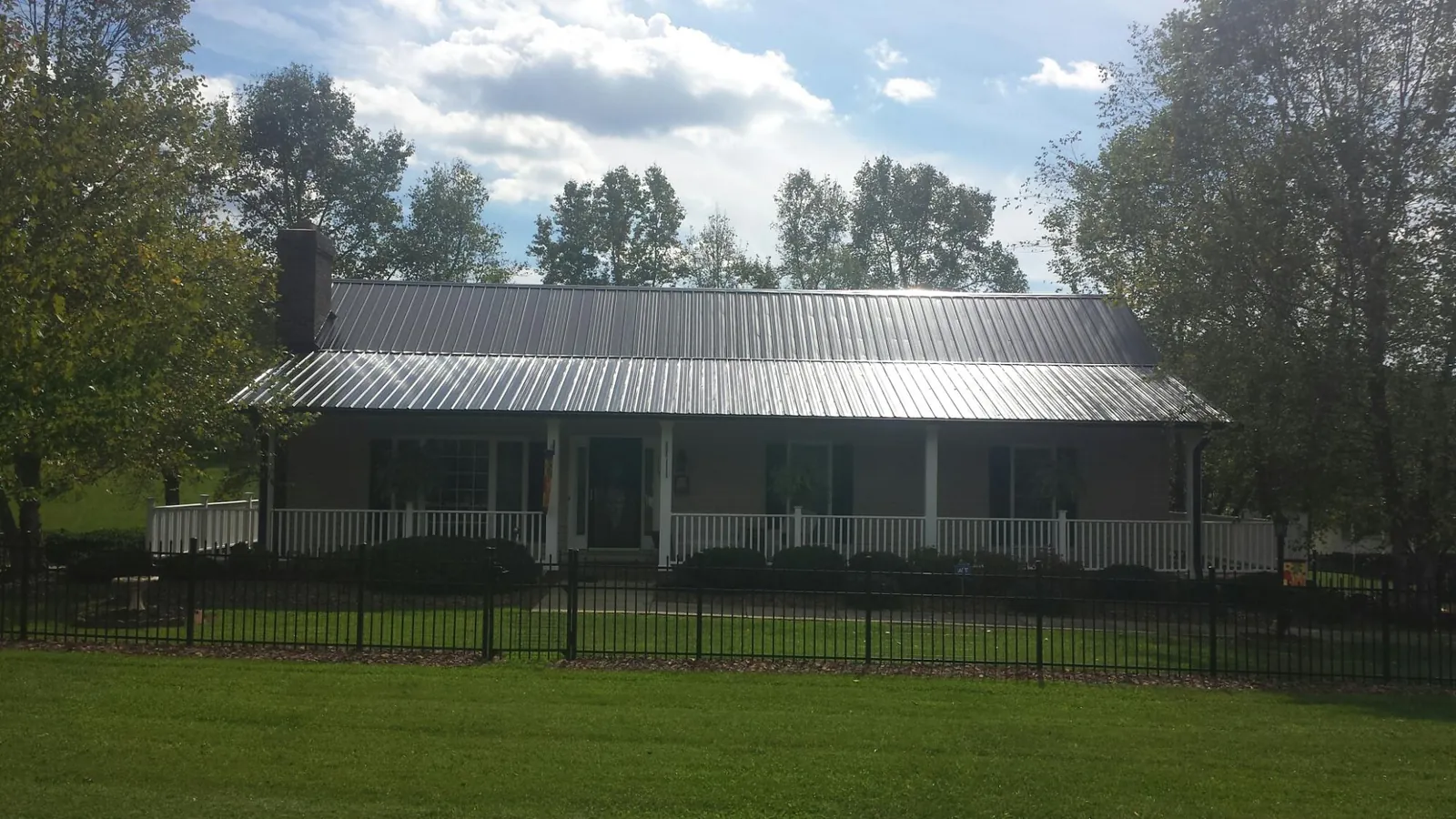 Gray metal roof on a brick ranch with a full width front porch — Gutter Guard Installation work by our crew in Bicknell