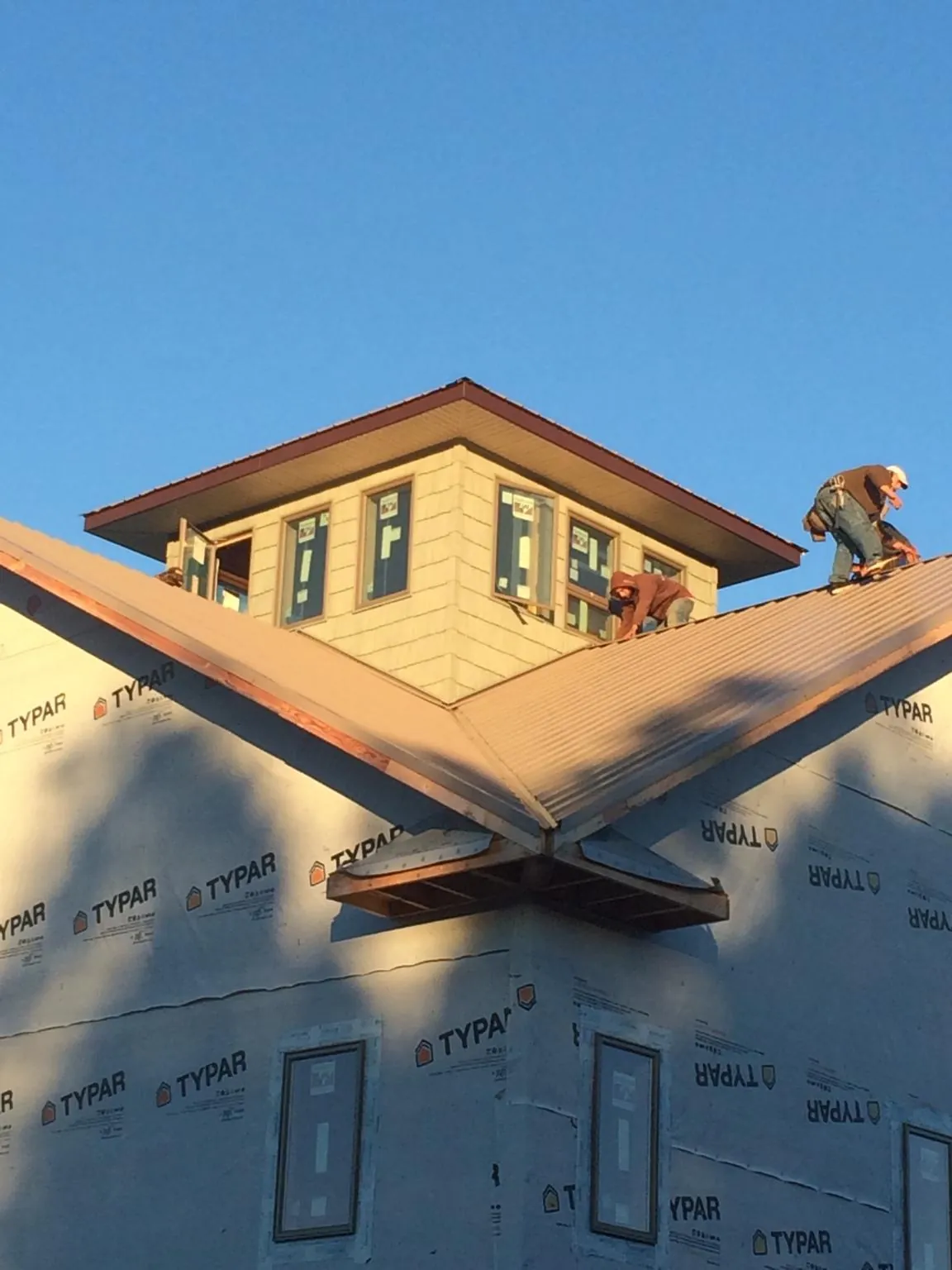 Roofers working around a rooftop cupola on a new metal roof at sunset — Roof Waterproofing in Bicknell by Roofing Brothers